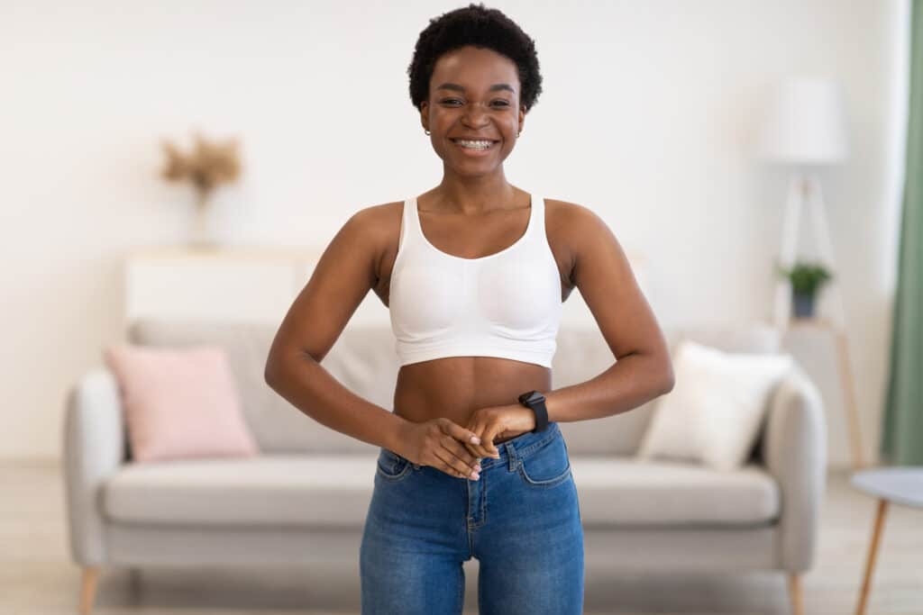 Smiling woman still fits in her skinny jeans after maintaining her weight.